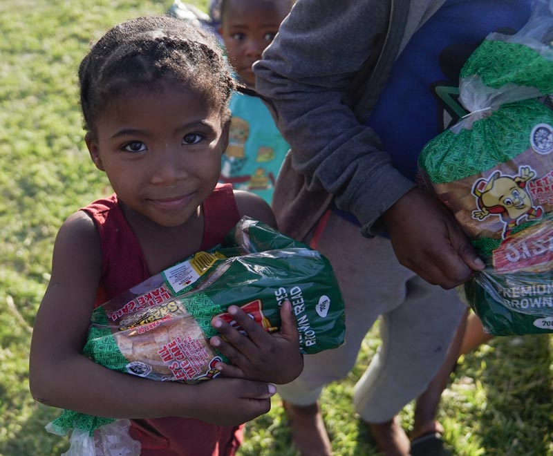A young girl holds onto a SASKO bag full of peanut butter and jam sandwiches that were donated on Mandela Day 2020